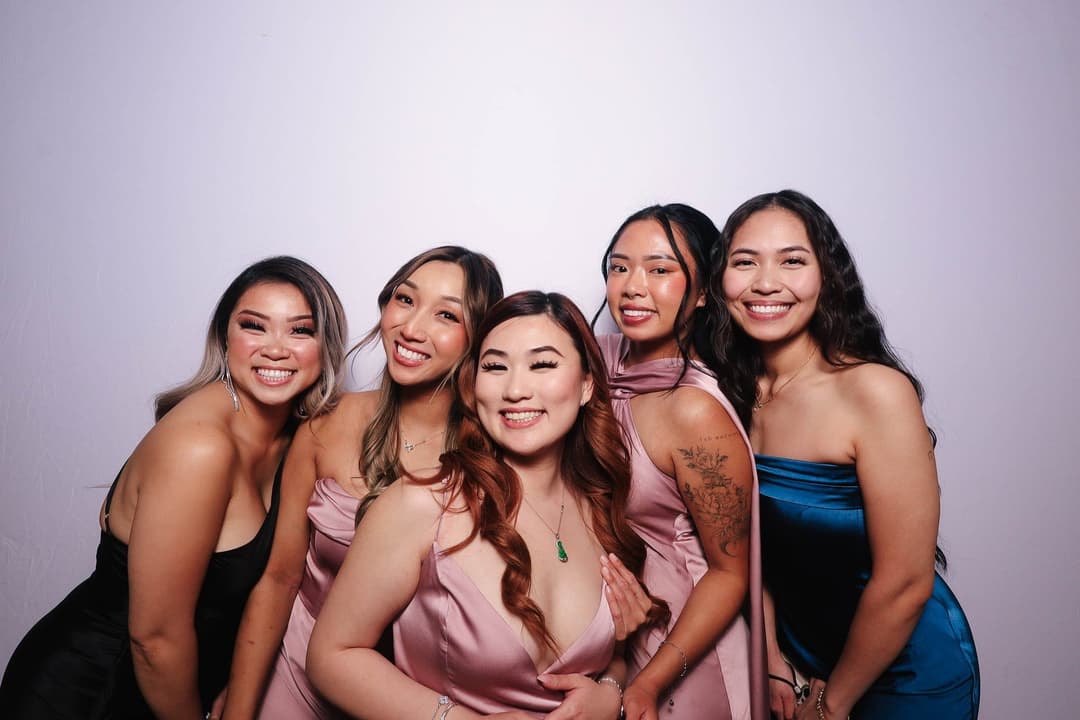 Five beautiful bridesmaids in pink and blue dresses smiling warmly together in group pose